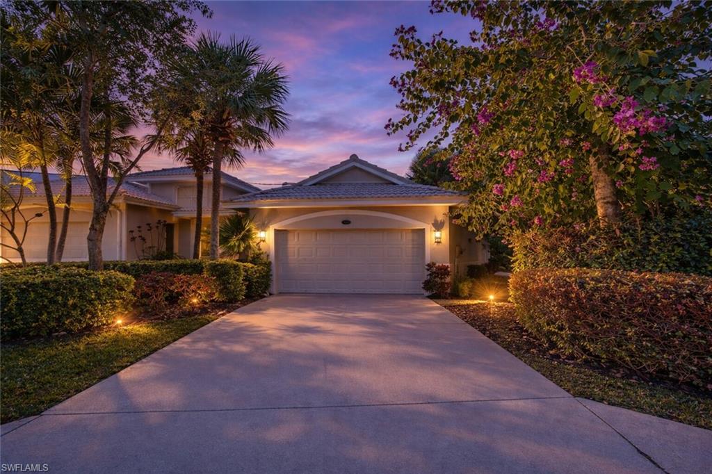 a front view of a house with a garden and tree