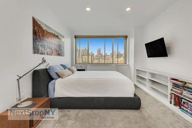 a spacious bedroom with a bed and a flat screen tv