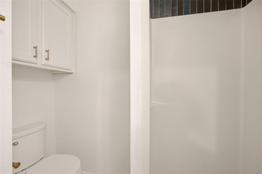 908 Isbell Road, Unit A Fort Worth, TX 76114 - Photo 22 of 28 White paneled cabinetry with brushed nickel hardware provides storage over a white commode