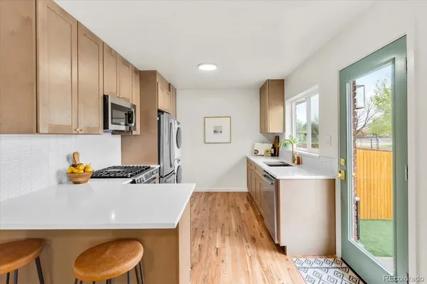 a kitchen with stainless steel appliances a sink a stove a refrigerator cabinets and a dining table