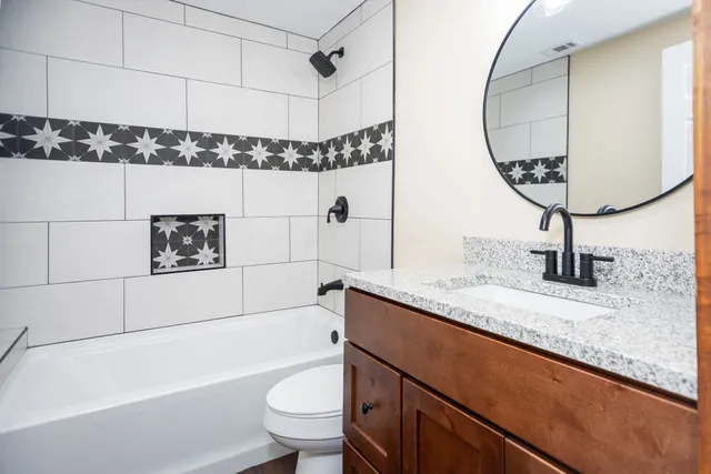 a bathroom with a granite countertop sink a toilet a mirror and shower