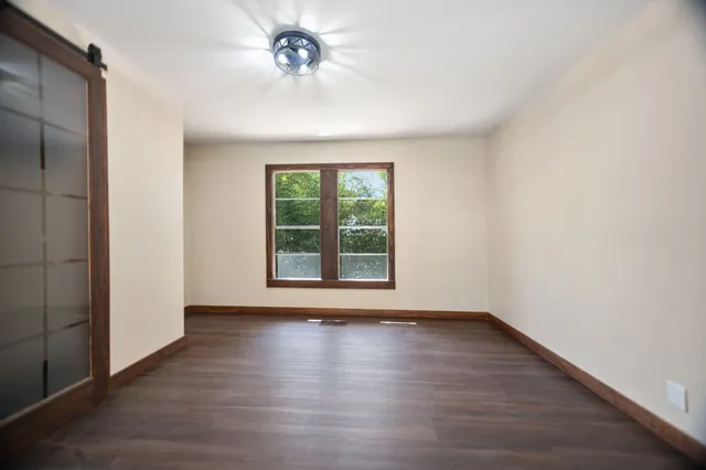 a view of an empty room with a window and wooden floor