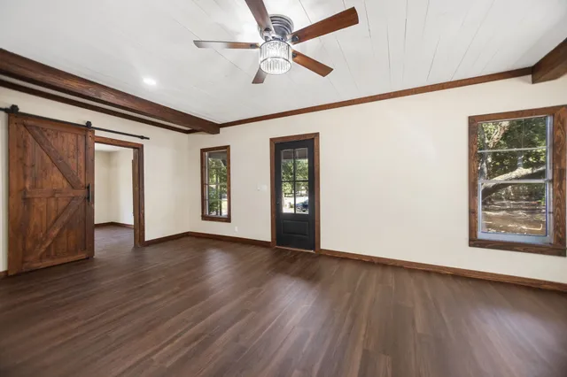 a view of an empty room with window and wooden floor