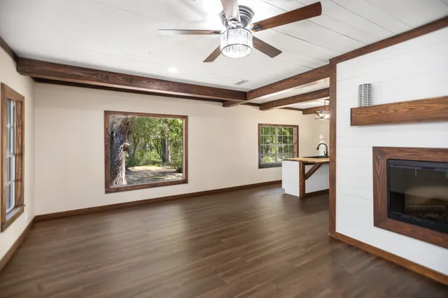 a view of an empty room with wooden floor fireplace and a window