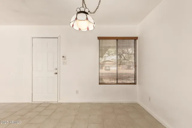 an empty room with chandelier fan and windows