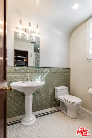 a view of an empty room with wooden floor and a kitchen