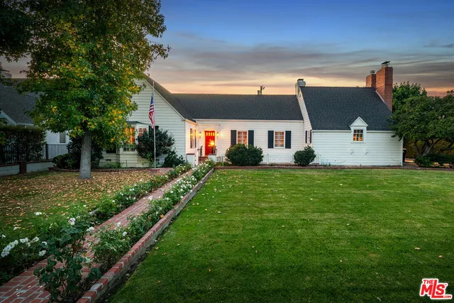 a front view of a house with a yard and trees