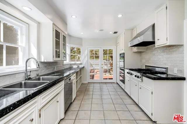 a large kitchen with granite countertop a stove a sink and a refrigerator