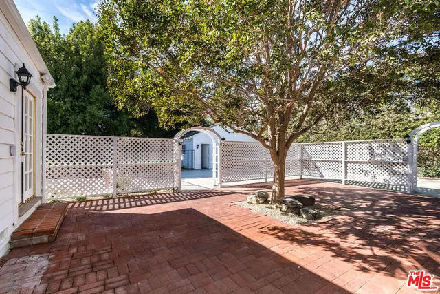 a view of a white house with a big yard and potted plants