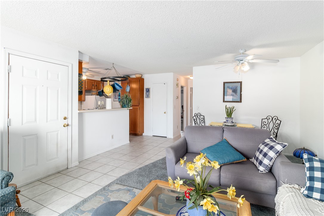 2192 Aspen Mirror Way, Unit 102 Laughlin, NV 89029 - Photo 11 of 58 Living room featuring light tile patterned flooring, a ceiling fan, and a textured ceiling