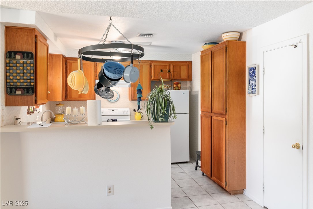2192 Aspen Mirror Way, Unit 102 Laughlin, NV 89029 - Photo 14 of 58 Kitchen with brown cabinets, light tile patterned floors, white appliances, light countertops, and decorative backsplash