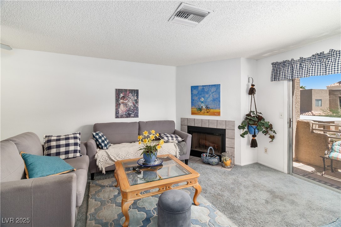 2192 Aspen Mirror Way, Unit 102 Laughlin, NV 89029 - Photo 8 of 58 Carpeted living area with a tiled fireplace and a textured ceiling