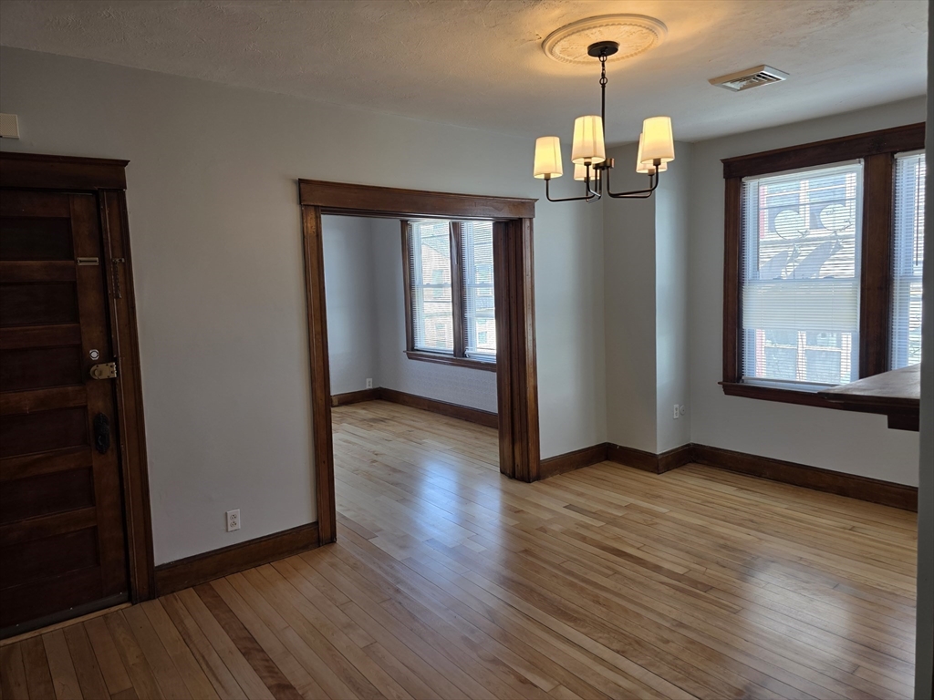 2 Hillside Street, Unit 3 Worcester, MA 01610 - Photo 21 of 30 an empty room with wooden floor chandelier and windows