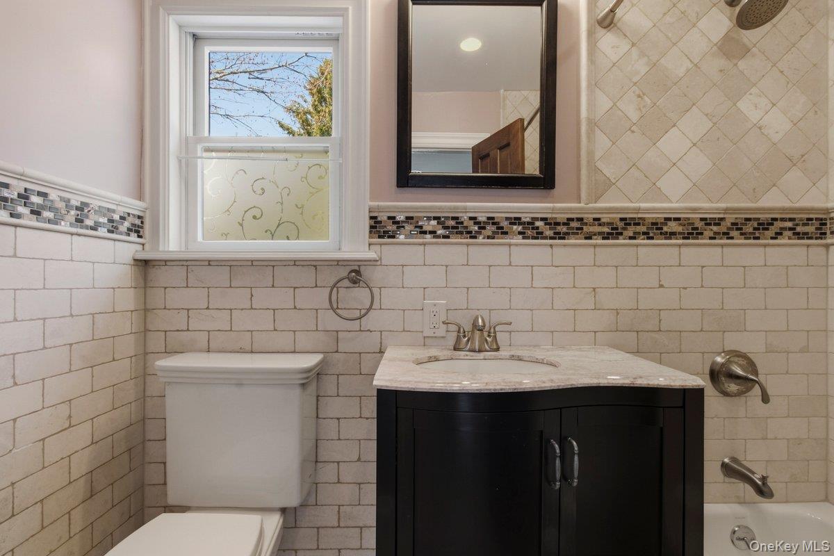 246 Tibbetts Road Yonkers, NY 10705 - Photo 6 of 27 Full bath featuring vanity, shower / washtub combination, wainscoting, and tile walls