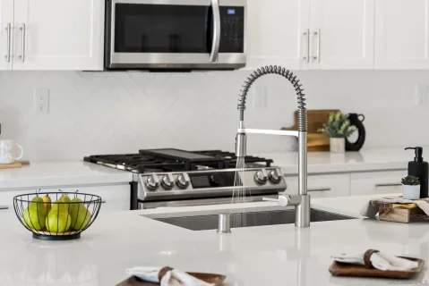 a kitchen that has a lot of white cabinets and stainless steel appliances