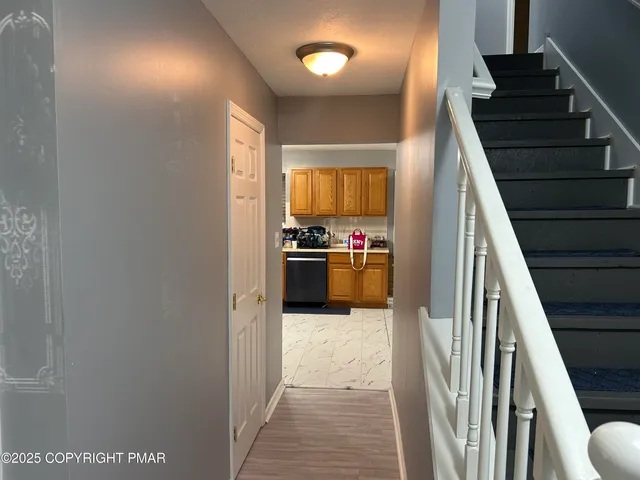 a view of a hallway to an empty room with wooden floor and stairs