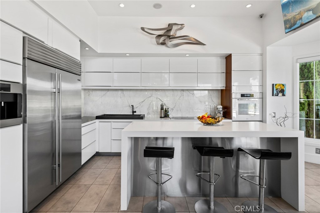 a kitchen with stainless steel appliances a table chairs refrigerator and sink