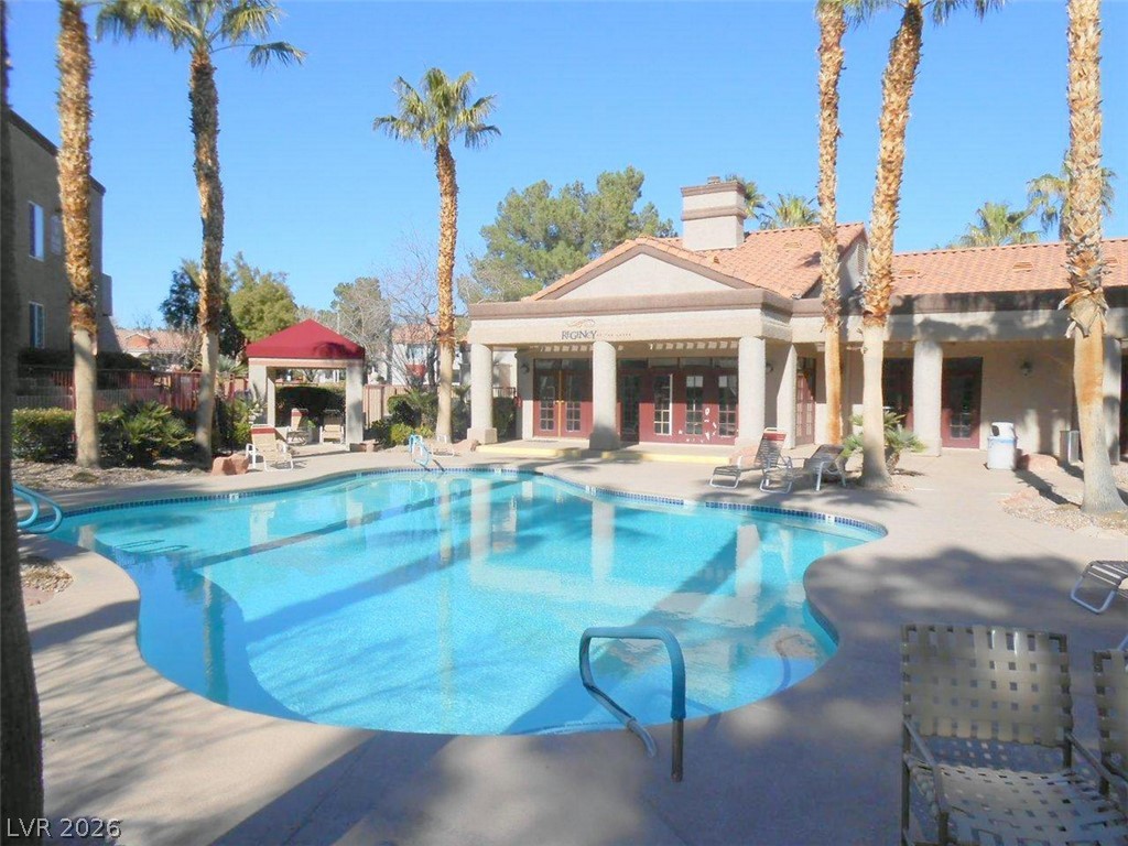 9325 West Desert Inn Road, Unit 132 Las Vegas, NV 89117 - Photo 30 of 36 A sparkling pool invites relaxation, set against a charming clubhouse and swaying palm trees.