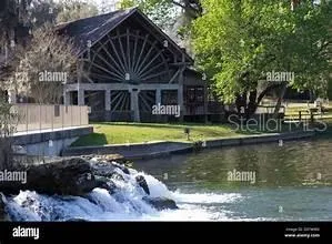a view of a large pool with lawn chairs under an umbrella