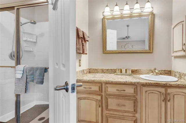 a bathroom with a granite countertop sink two mirror and shower