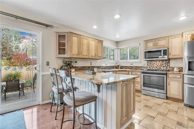 a kitchen with stainless steel appliances granite countertop a stove top oven a sink dishwasher and a refrigerator