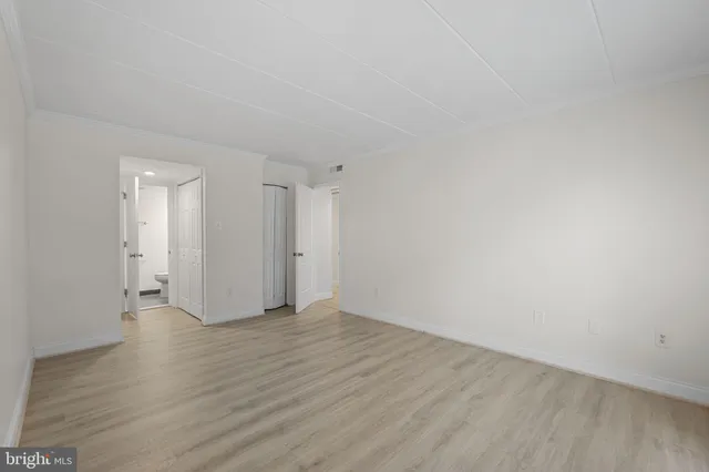 a view of an empty room with wooden floor and closet