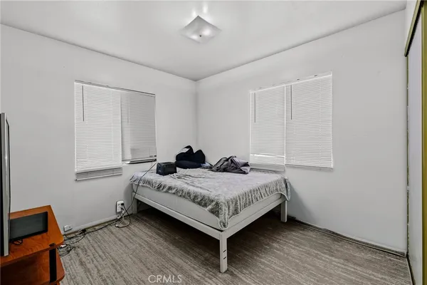 a bedroom with a bed tv and a window