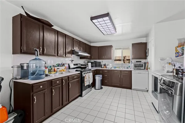 a kitchen with stainless steel appliances granite countertop a stove top oven a sink dishwasher and a refrigerator