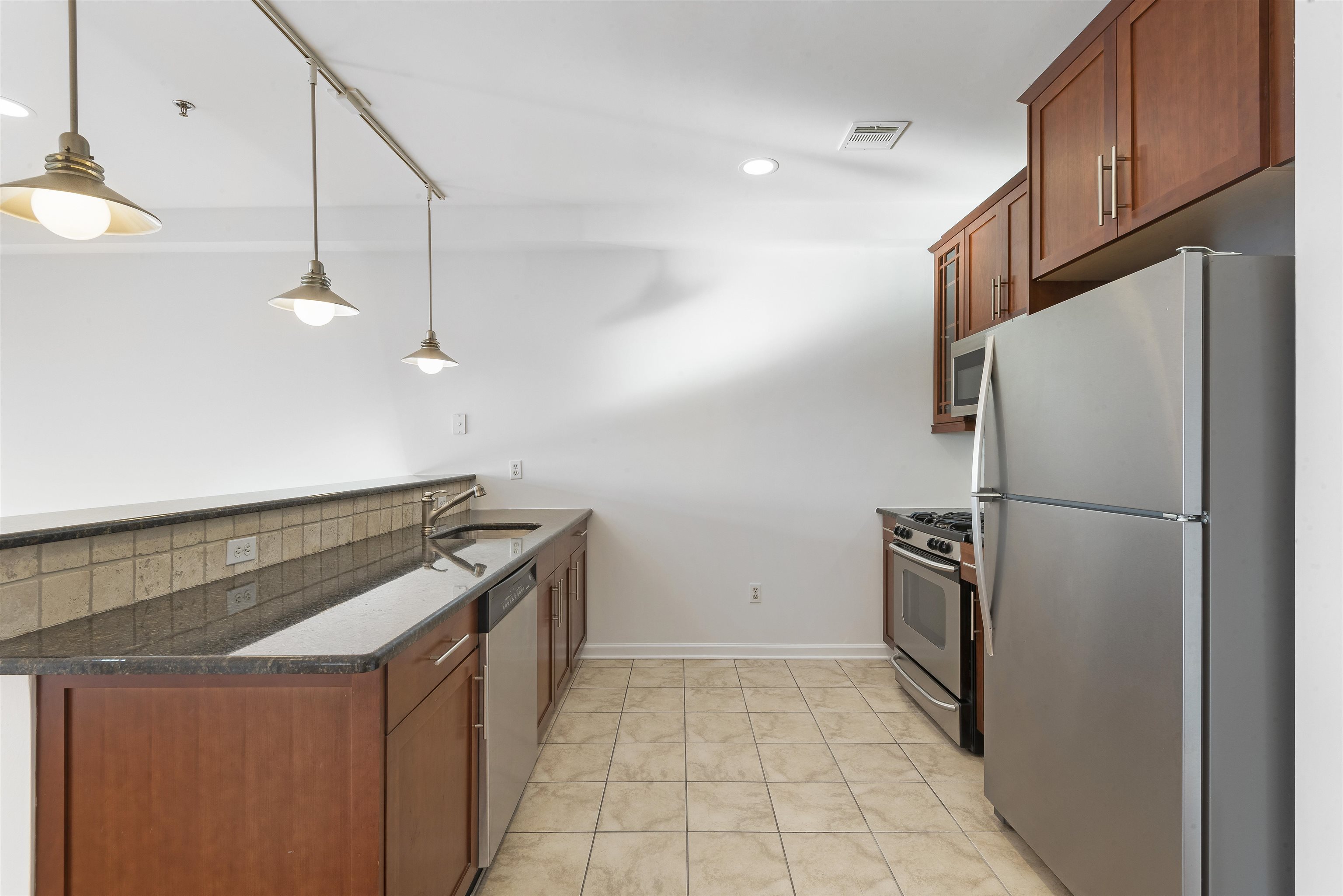 203-207 Hackensack Plank Road, Unit 5B Weehawken, NJ 07086 - Photo 4 of 18 a kitchen with granite countertop a refrigerator and a stove
