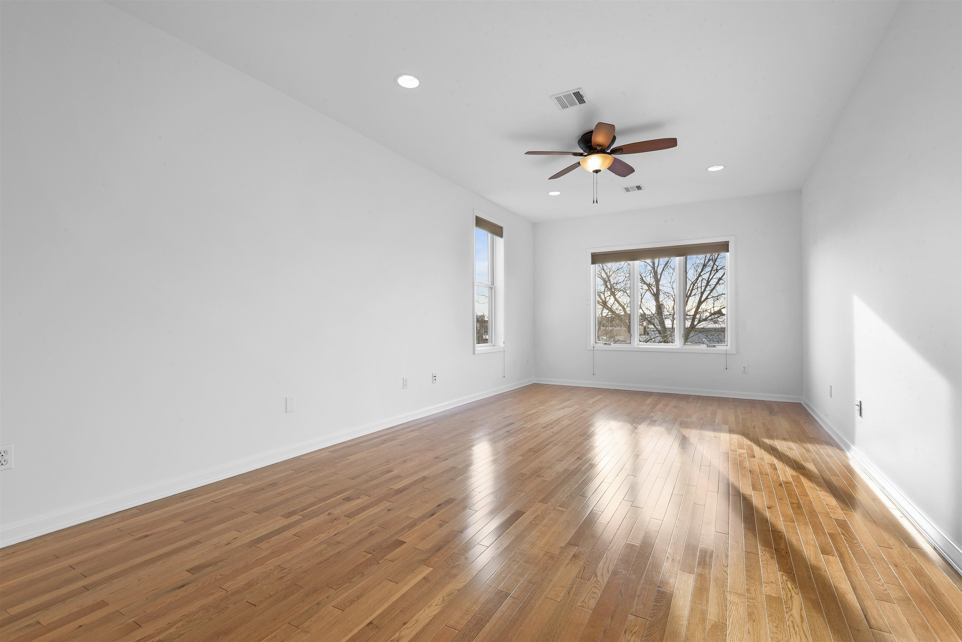 203-207 Hackensack Plank Road, Unit 5B Weehawken, NJ 07086 - Photo 9 of 18 an empty room with wooden floor ceiling fan and windows