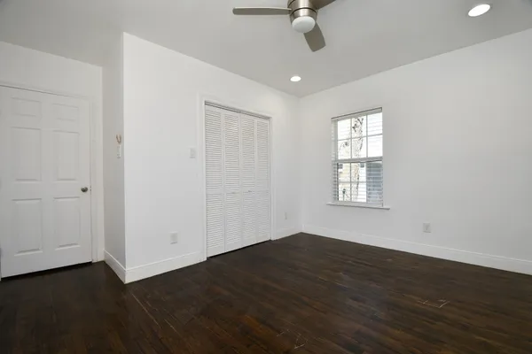 an empty room with wooden floor fan and windows