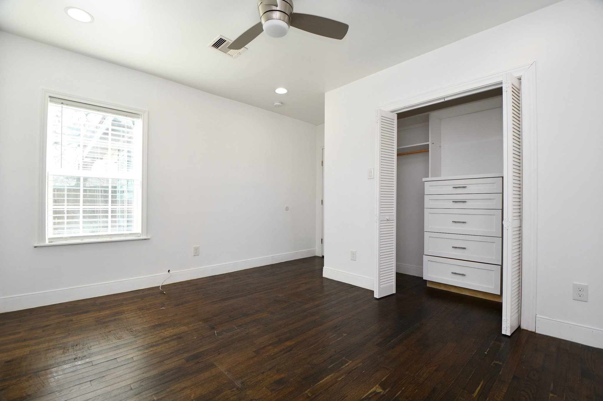 3803 Arbor Street Houston, TX 77004 - Photo 13 of 19 Bright, airy room with dark hardwood floors, a ceiling fan, and a window providing natural light. Features a closet with built-in drawers, perfect for storage.