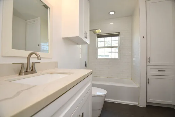 a bathroom with a bathtub sink vanity mirror and toilet