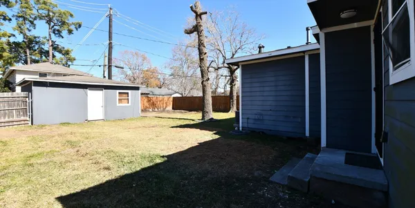 a backyard of a house with wooden fence and trees