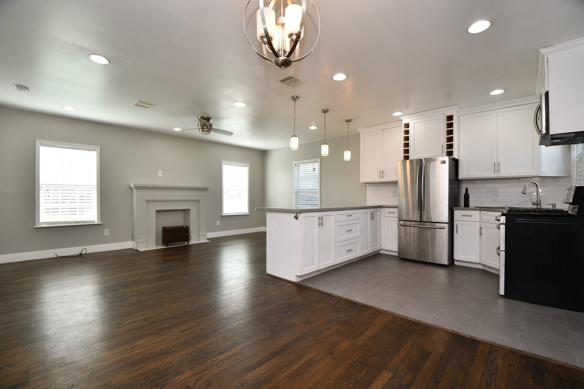 3803 Arbor Street Houston, TX 77004 - Photo 4 of 19 This open-concept kitchen and living area features modern lighting, hardwood floors, and a sleek, stainless steel refrigerator. The kitchen has white cabinetry and a spacious layout, while the living area with ample natural light from multiple windows.