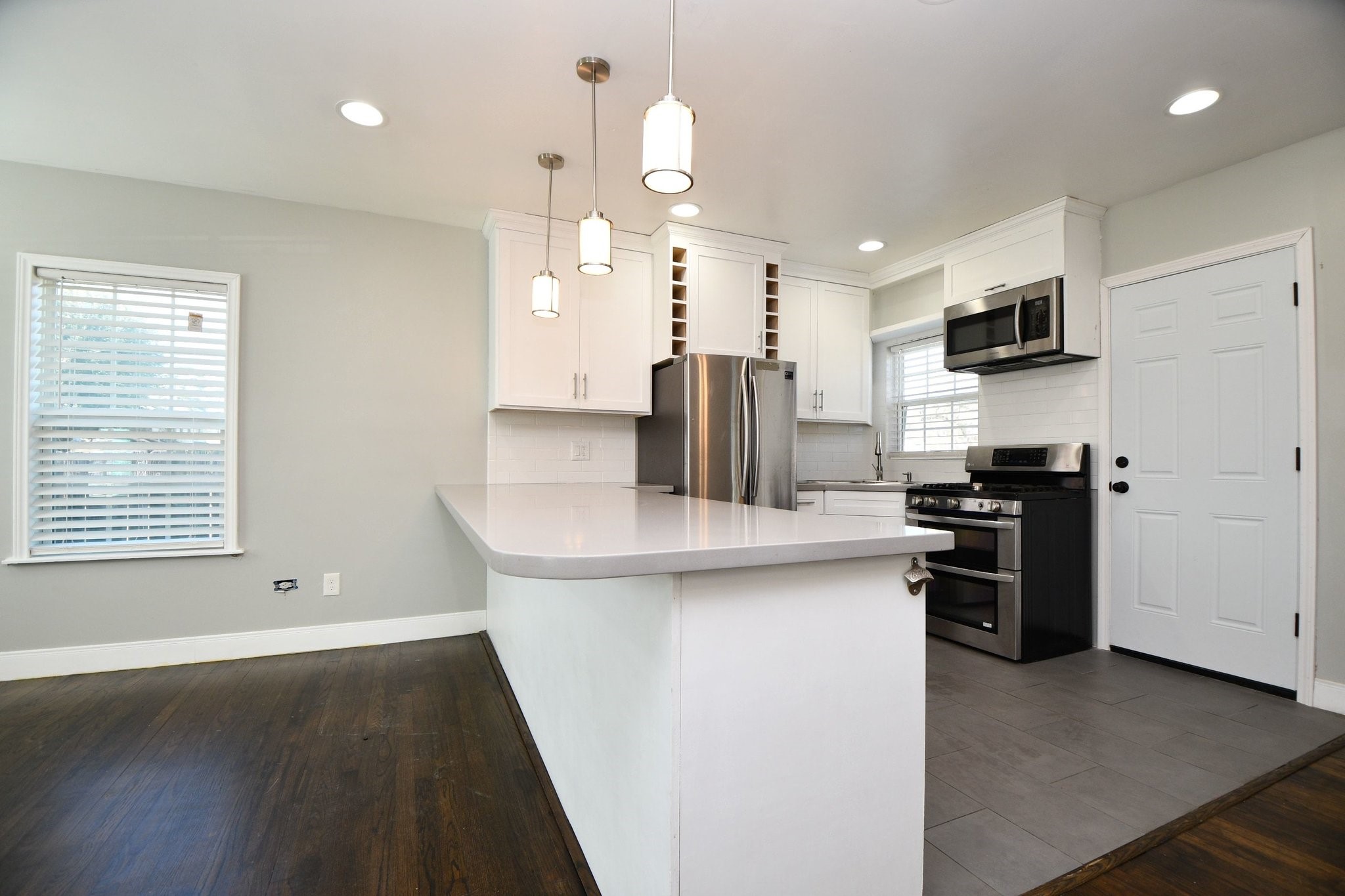 3803 Arbor Street Houston, TX 77004 - Photo 7 of 15 This modern kitchen features sleek white cabinetry, stainless steel appliances, and a spacious island with pendant lighting. The open layout and large windows provide ample natural light, enhancing the contemporary design.