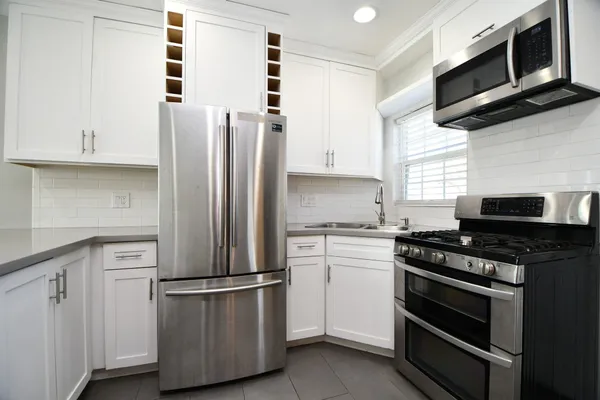 a kitchen with cabinets stainless steel appliances and wooden floor
