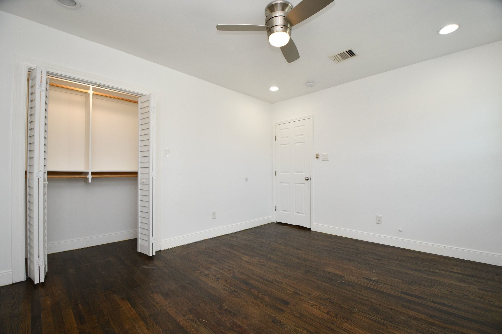 3803 Arbor Street Houston, TX 77004 - Photo 8 of 15 This room features hardwood floors, a ceiling fan, recessed lighting, and a spacious closet with louvered doors. The walls are painted white, creating a bright and clean atmosphere.
