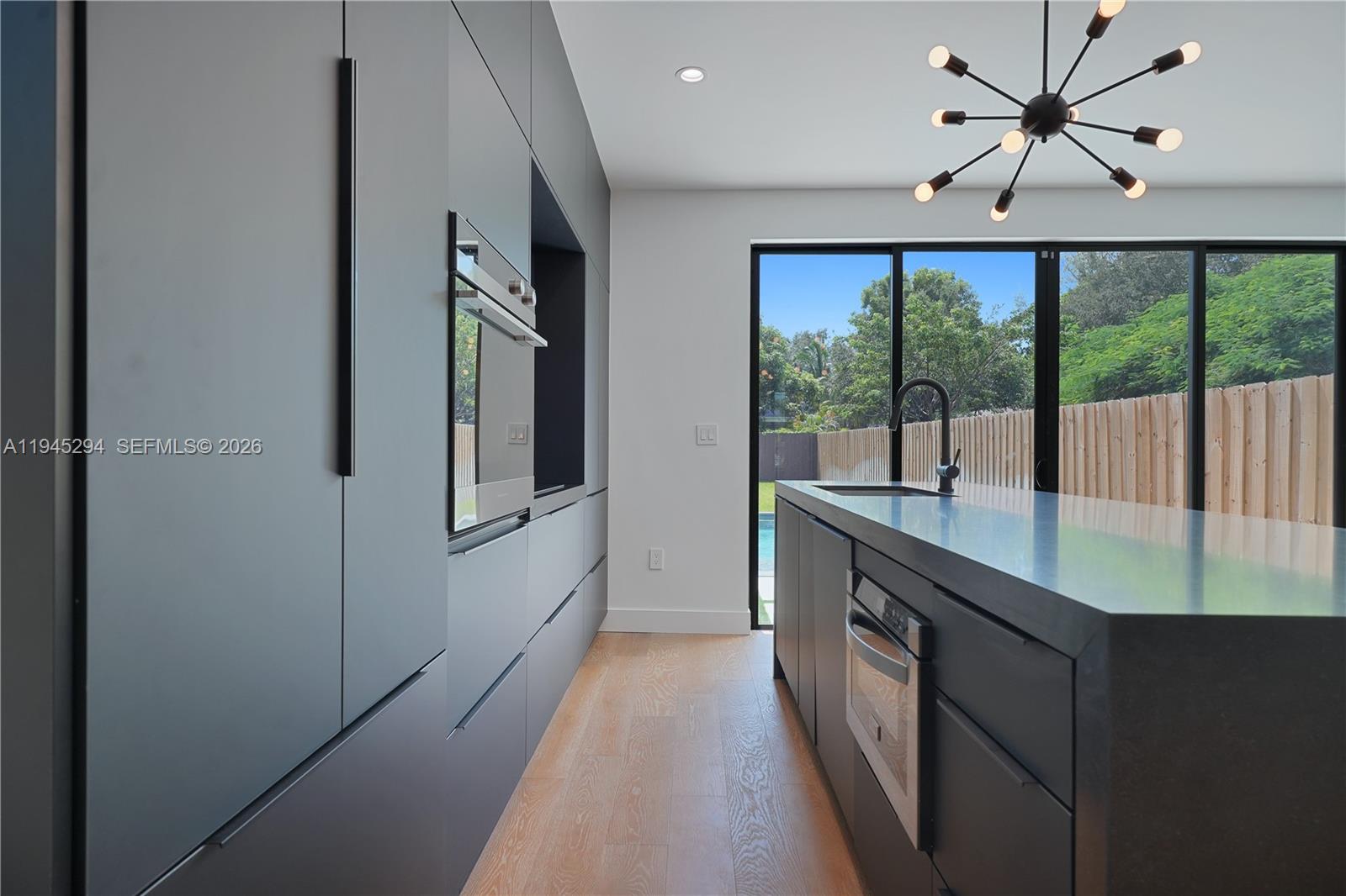 355 Northwest 50th Street Miami, FL 33127 - Photo 13 of 25 a kitchen with kitchen island a large window a sink and stainless steel appliances