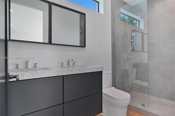 a bathroom with a toilet a sink a mirror and shower