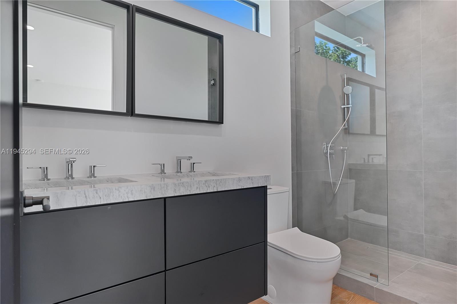 355 Northwest 50th Street Miami, FL 33127 - Photo 17 of 25 a bathroom with a toilet a sink a mirror and shower