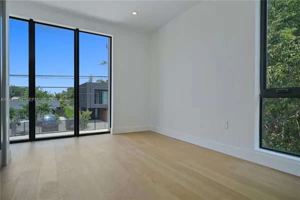 an empty room with sliding glass door and wooden floor