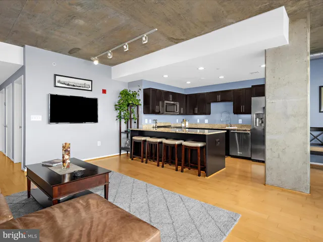 a living room with stainless steel appliances furniture and a flat screen tv