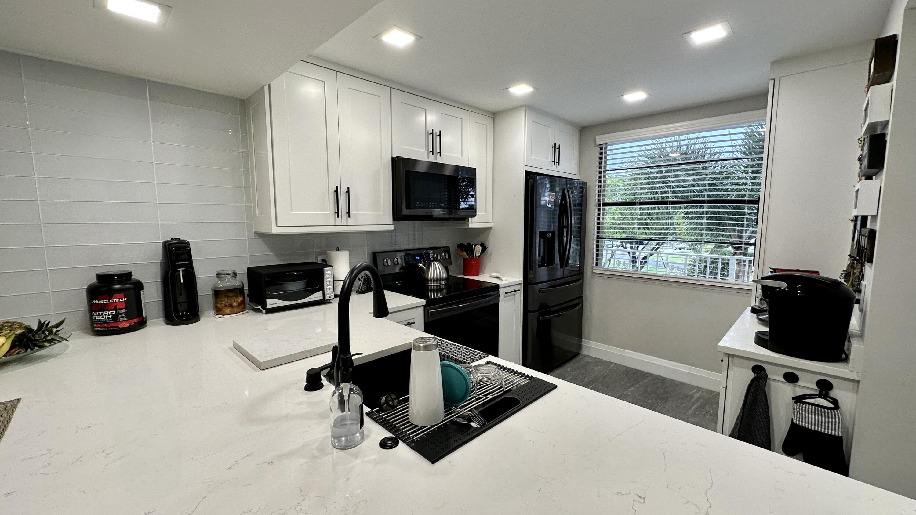 6073 Balboa Circle, Unit 305 Boca Raton, FL 33433 - Photo 1 of 29 a kitchen with stainless steel appliances kitchen island granite countertop a refrigerator and a sink