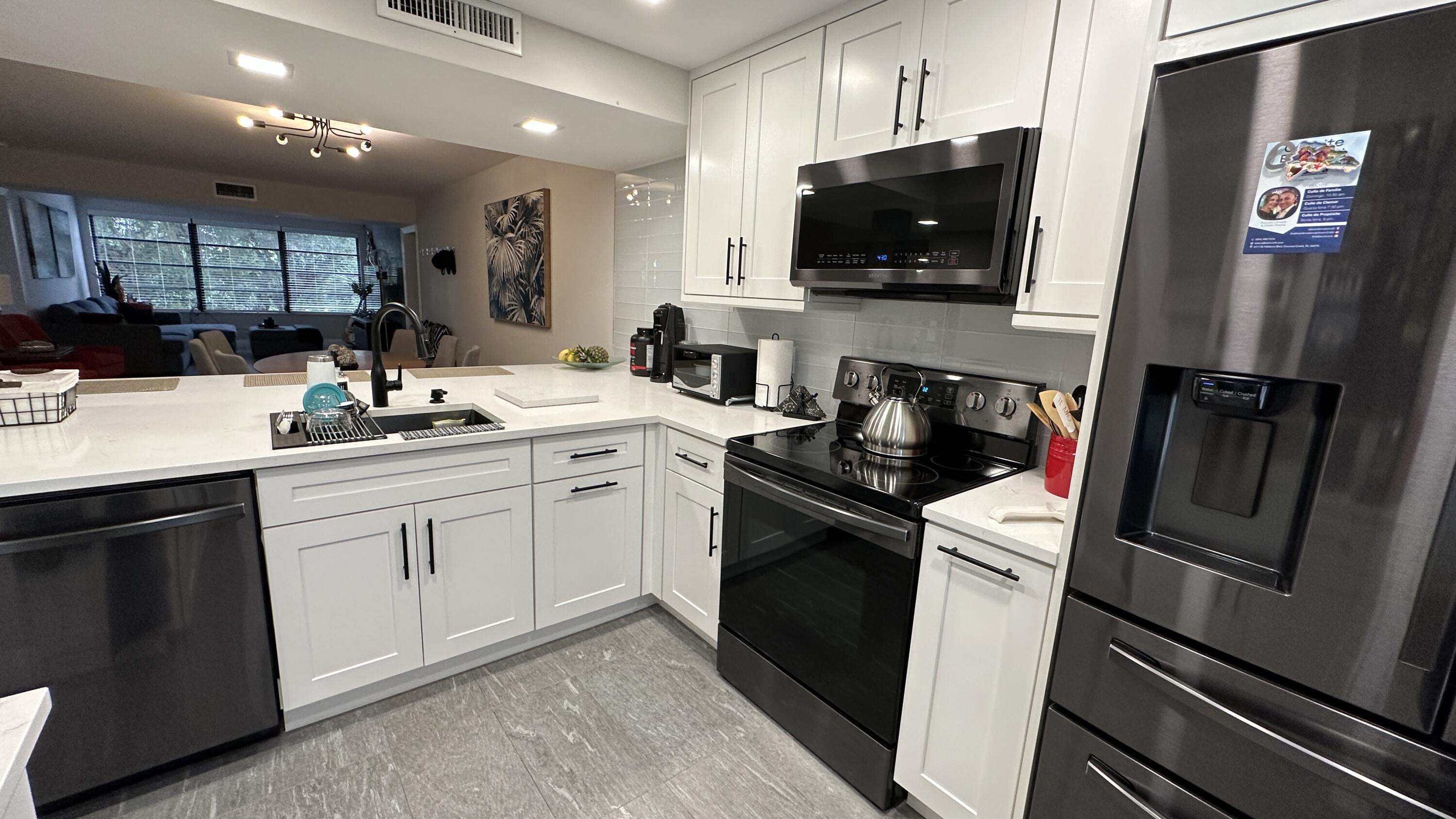 6073 Balboa Circle, Unit 305 Boca Raton, FL 33433 - Photo 3 of 29 a kitchen with a sink stainless steel appliances and cabinets