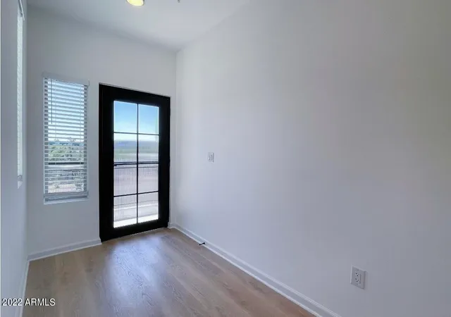 a view of an empty room with window and wooden floor