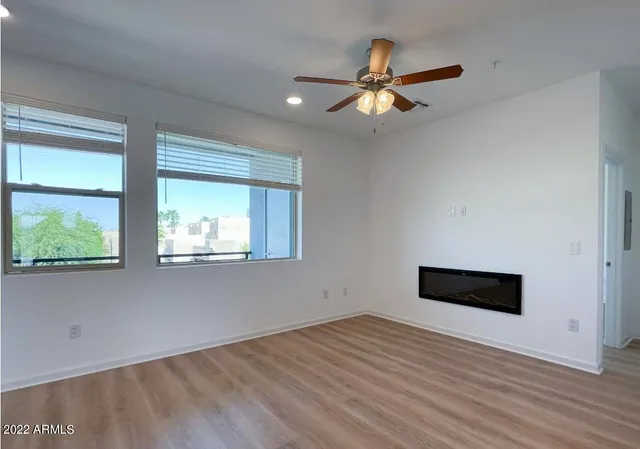 a view of empty room with wooden floor and fan