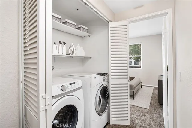 a view of washer and dryer with bathroom in the background
