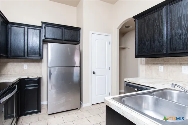 a kitchen with metallic refrigerator freezer and a sink