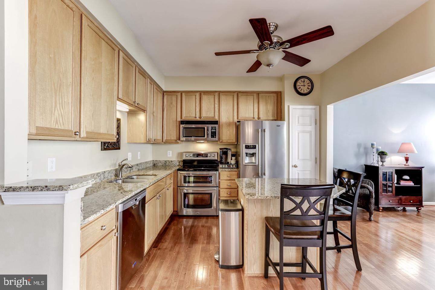 10106 Sir Reynard Lane Bristow, VA 20136 - Photo 7 of 28 a kitchen with stainless steel appliances granite countertop a stove top oven a refrigerator a sink and chairs